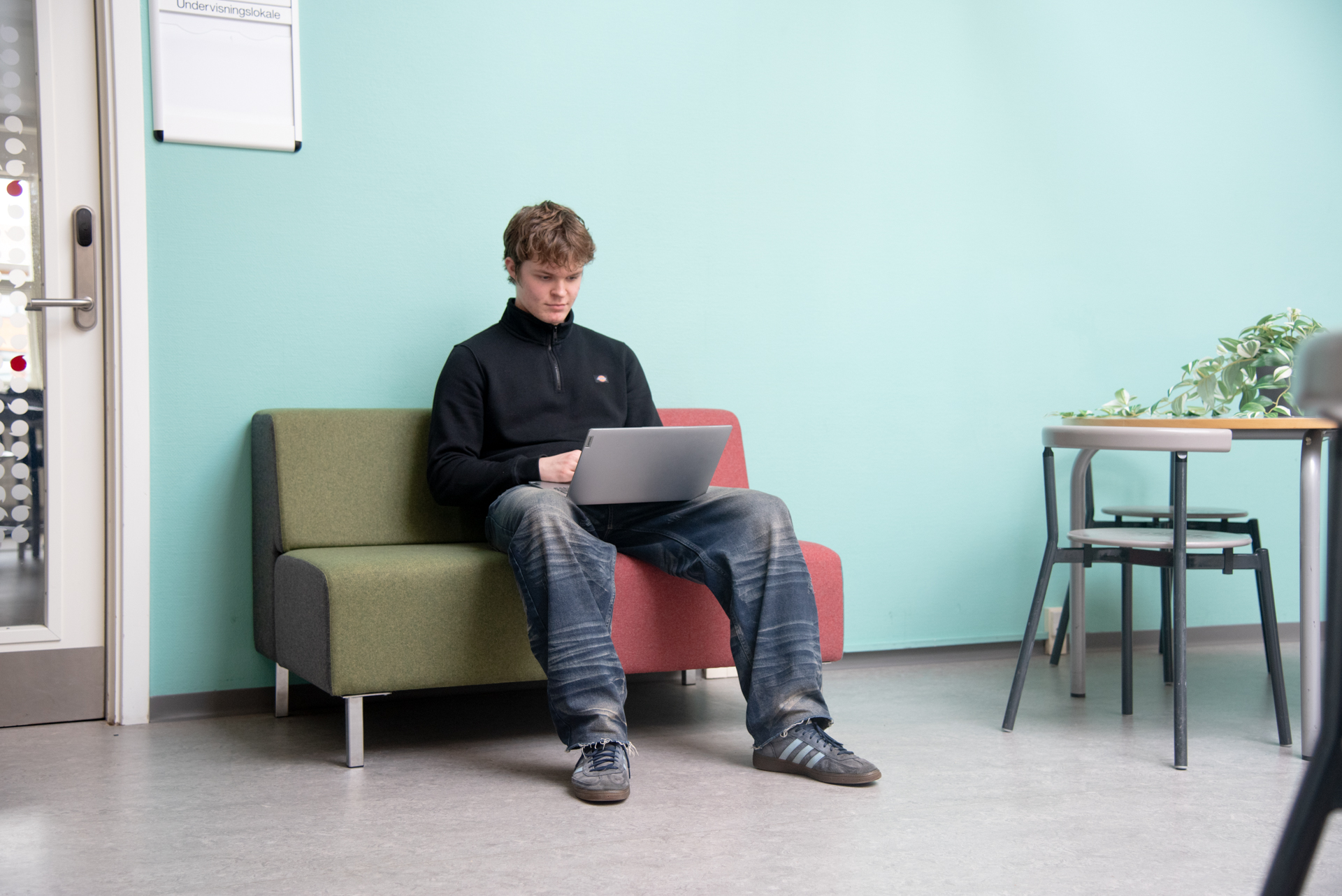 Pige med computer der sidder på en gren